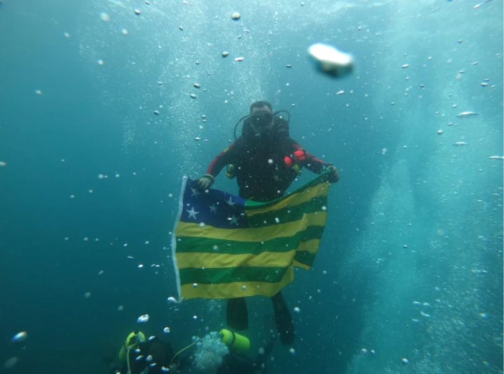 Mergulhador em água doce segurando a bandeira de Goiás